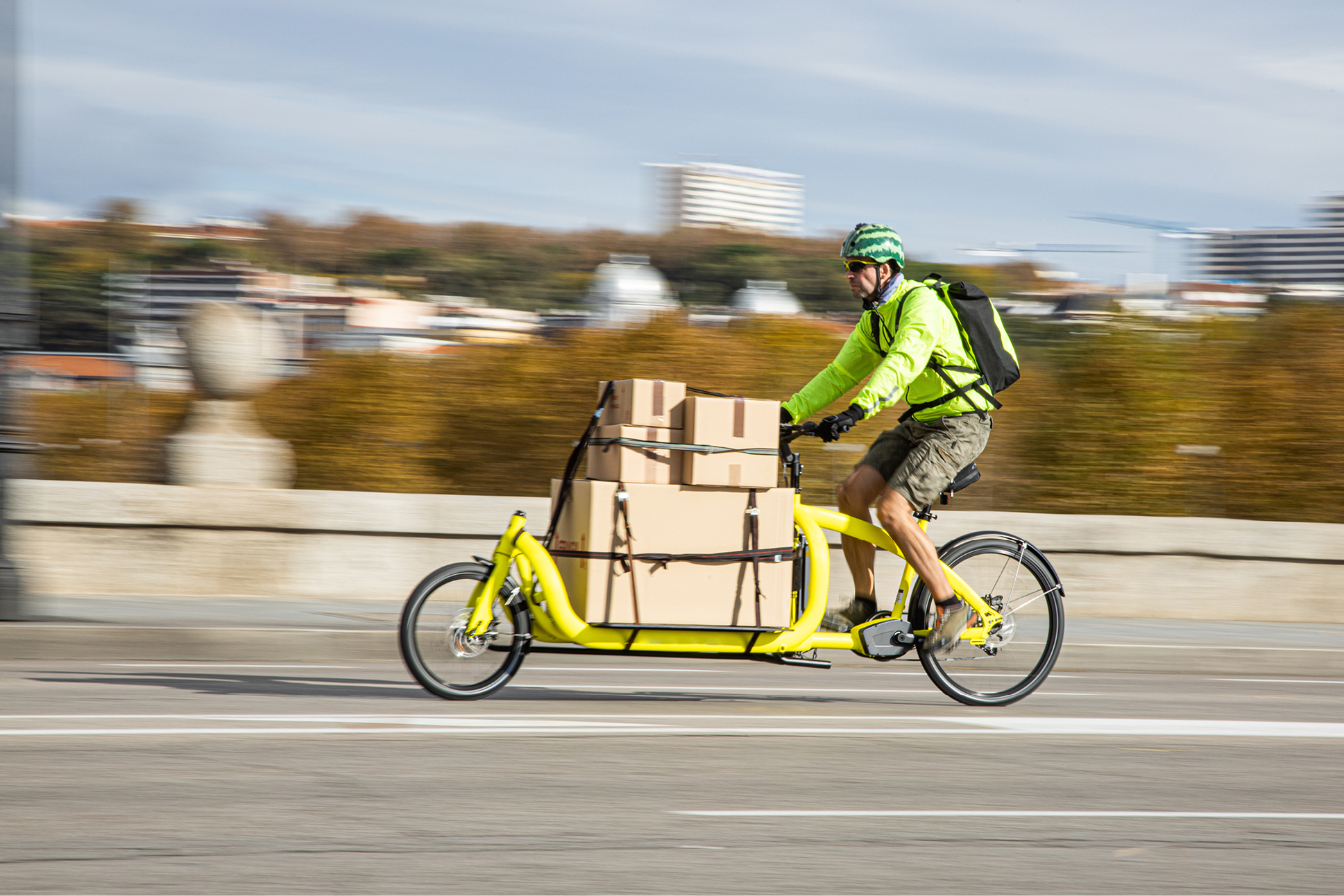 A person riding a cargo bicycle loaded with cardboard boxes.