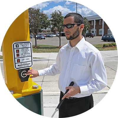 Image of a blind man activating a pedestrian signal at a crosswalk