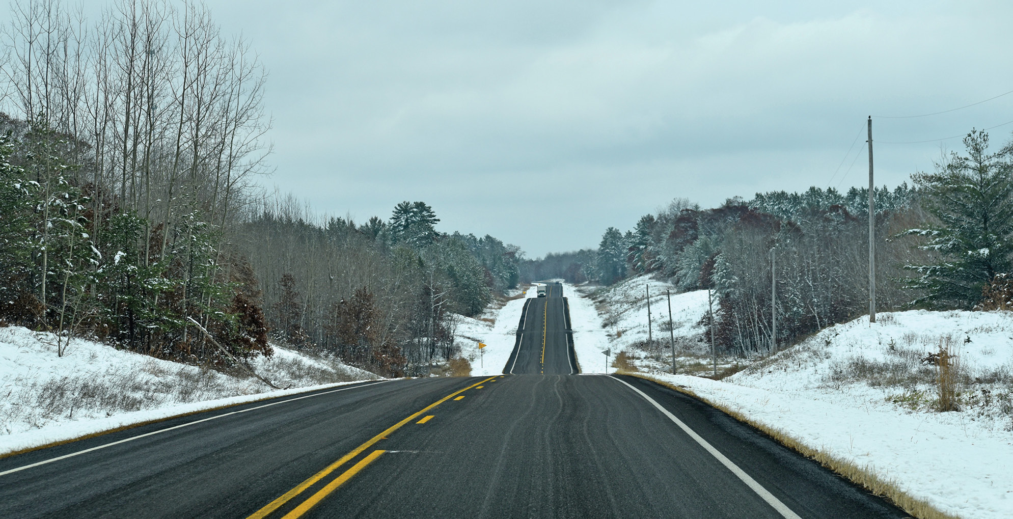 A Minnesota roadway surrounded by snow showing asphalt in good condition.